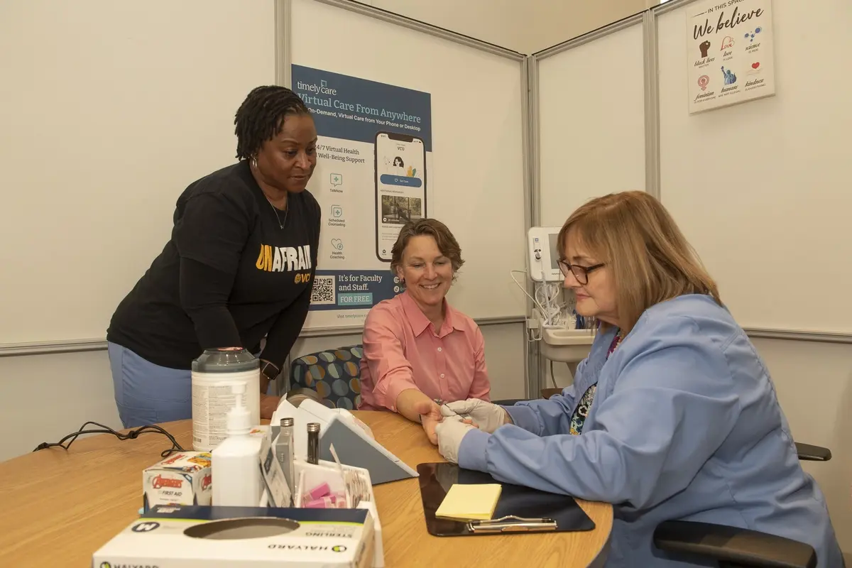 Individual getting her blood pressure checked with two other women